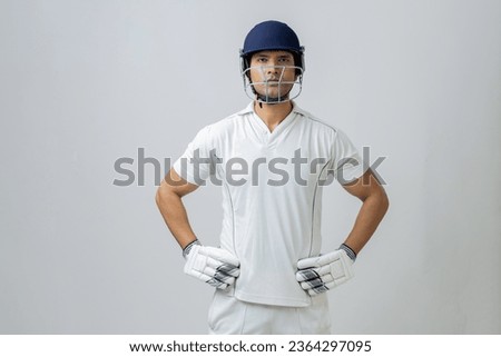 portrait of indian Man in cricket dress with helmet and gloves. Cricketer portrait in studio light looking towards the camera