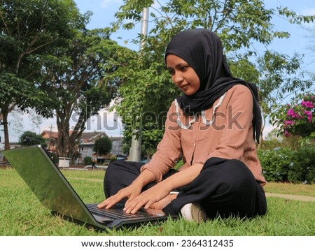 Portrait of Arab business Women working on laptop sitting at city park. Freelancer muslim woman using laptop for work. Copy space