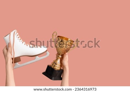 Female hands with gold cup and ice skate on pink background