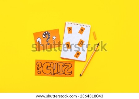 Notebook with paper quiz card and question marks on yellow background