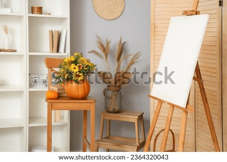 Interior of living room with pumpkins on chair and easel