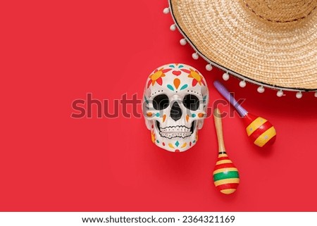 Painted human skull for Mexico's Day of the Dead (El Dia de Muertos) with sombrero and maracas on red background Royalty-Free Stock Photo #2364321169