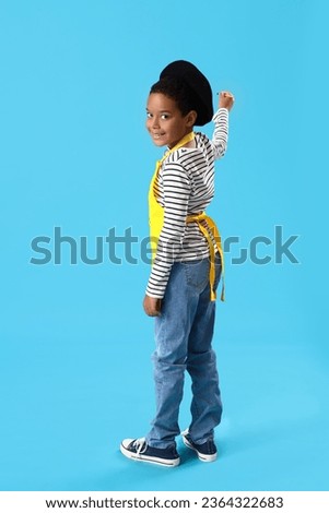 Little African-American boy with paint brush on blue background