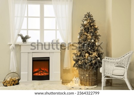 Interior of festive living room with fireplace and Christmas tree near window