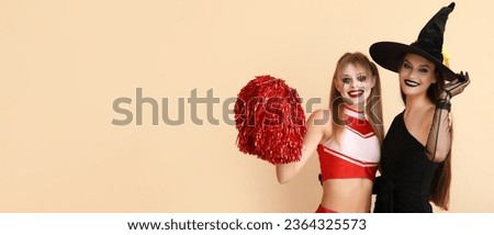 Young women dressed for Halloween on beige background with space for text