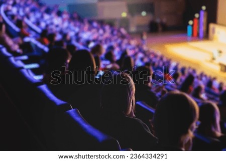 Audience at the modern conference hall listens to panel discussion, people on a congress together listen to speaker on stage at convention, business seminar, amphitheater venue for congress Royalty-Free Stock Photo #2364334291