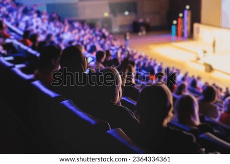 Audience at the modern conference hall listens to panel discussion, people on a congress together listen to speaker on stage at convention, business seminar, amphitheater venue for congress Royalty-Free Stock Photo #2364334361