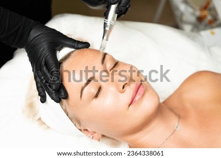 Microneedle RF lifting procedure. A cosmetologist performs a facial rejuvenation procedure on a woman. Hardware cosmetology. Royalty-Free Stock Photo #2364338061