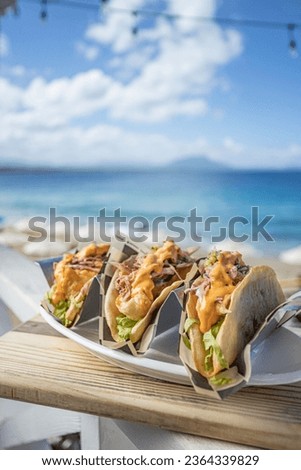 The fresh prepared tacos on the wooden board on the background of the beach