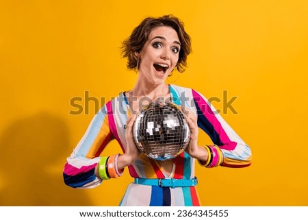 Photo of positive young girl 90s discotheque party nightclub weekend astonished demonstrate shine ball isolated on yellow color background