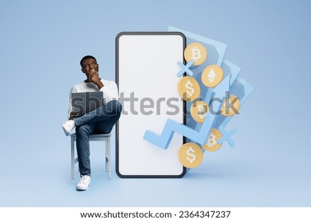 Cheerful young black man trader using laptop, sitting by huge phone with white blank screen, money cash 3d illustration on blue background. Trading on stock and markets online, mockup, blank space
