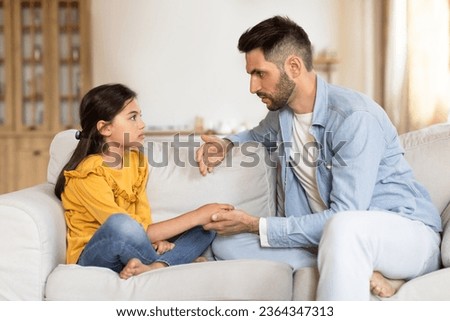 Supportive Arabic Dad Talking To Sad Preteen Daughter, Supporting Her In Childhood Struggles, Sitting On Couch, Explaining Something And Helping Cope With Adolescence Problems At Home Royalty-Free Stock Photo #2364347313