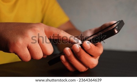 the hand of a person in a yellow shirt whose finger is pointing at the smartphone screen