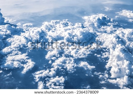 Aerial view of land, sea, soft white clouds from window of flying aeroplane. Fluffy cotton cumulus cloud in blue sky, islands and water, top view. Beauty blue high up cloudscape at sunlight day Royalty-Free Stock Photo #2364378009