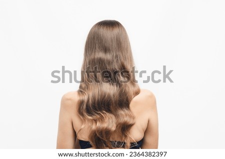 Woman with long wavy hair standing with her back to the camera