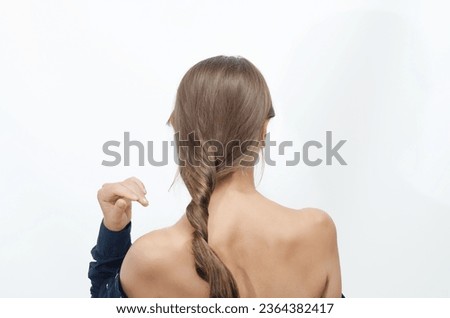 Woman stands with her back to the camera, hair tied up in a cord Royalty-Free Stock Photo #2364382417