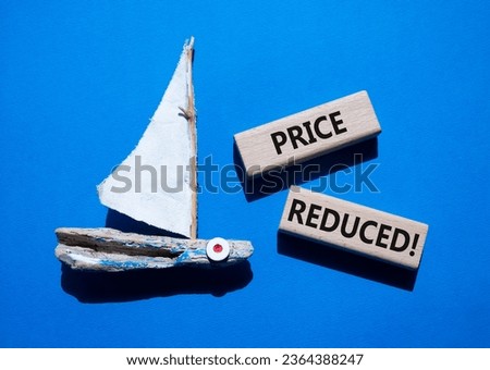 Price reduced symbol. Concept word Price reduced on wooden blocks. Beautiful blue background with boat. Business and Price reduced concept. Copy space