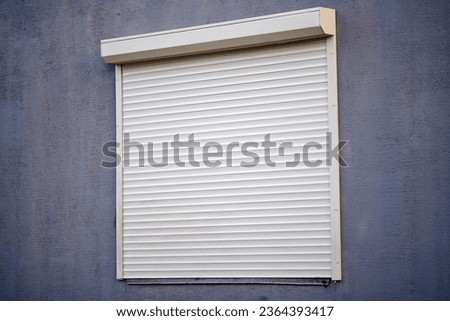 Rolling shutters, window with closed roller shutters. House facade with window on first floor, security and protection concept Royalty-Free Stock Photo #2364393417