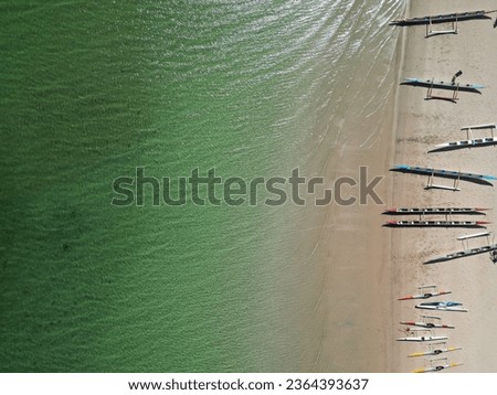 A drone view of boats placed in a row along the beach shore