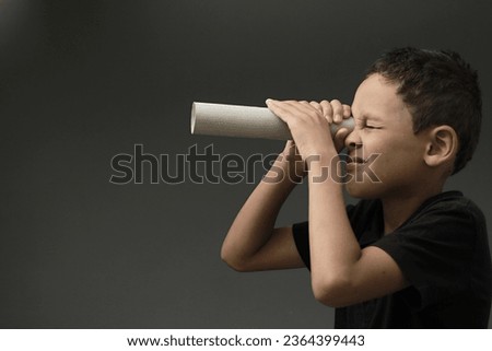 boy looking  through toy binoculars made from toilet paper roll on grey background with people stock image stock photo