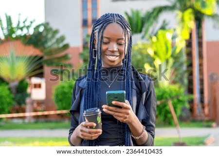 young black woman with blue braids scrolling through her phone while enjoying a cup of coffee