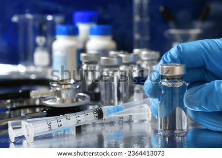 Medical personnel picking up vial of generic vaccine with more immunizations and syringes in background Royalty-Free Stock Photo #2364413073