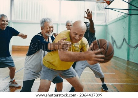 Diverse group of male seniors playing basketball in an indoor basketball gym Royalty-Free Stock Photo #2364437899
