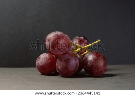 The Picture of the sweet grape with dark red grapefruit and dark gray background.