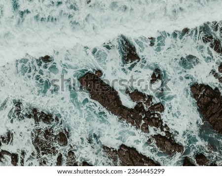 Stunning aerial views of Great Ocean Road beaches: vivid blue waters contrast with rugged brown rocks. Artistic wave patterns captured in both natural and long-exposure shots for abstract elegance.