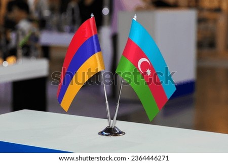 Two small table flags of Azerbaijan and Armenia together at some event or fair, as a symbol of cooperation between the two states. Joint business of Armenia and Azerbaijan Royalty-Free Stock Photo #2364446271
