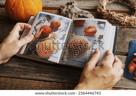 Photo printing, Thanksgiving day memories. Female hands holding picture album with autumn printed photos.