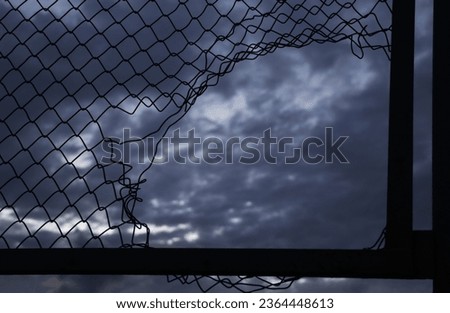 Opening in metallic net fence. isolated on blue sky background. Challenge. uncertainty. breakthrough concept. freedom concept. Chainlink, wire netting, wire-mesh.