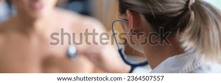 Female cardiologist examines heart health of male patient in medical clinic. Concept of cardiology and medical examination.