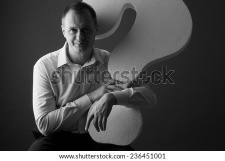 Smiling businessman with question mark, studio portrait