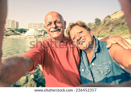 Senior happy couple taking a selfie at Blue Grotto resort in Malta south coast - Adventure travel to mediterranean islands - Concept of active elderly and fun around the world - Vintage filter