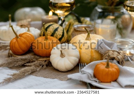 utumn cozy mood table composition for family thanksgiving dinner with wine, pumpkins, candles on wooden tray. Fall mood, warm plaid. Hygge home decor, interior seasonal design