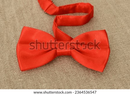 Stylish red bow tie on natural linen texture.