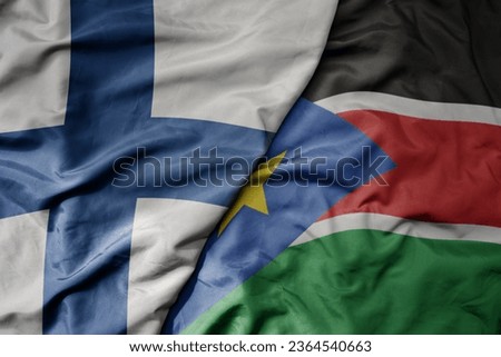 big waving national colorful flag of finland and national flag of south sudan . macro