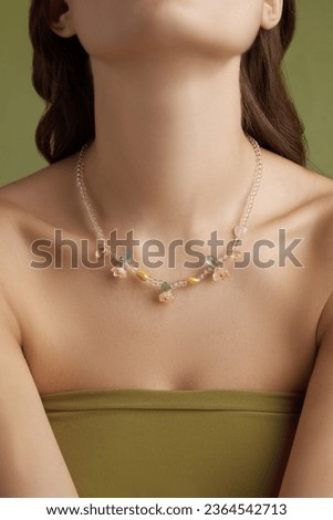 Close-up shot of a young woman wearing a handmade beaded necklace. Chain around the woman's neck of multi-colored beads. Handmade jewelry made out of beads. Front view.                    
