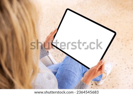 Woman holding tablet computer in hands, empty white screen mockup