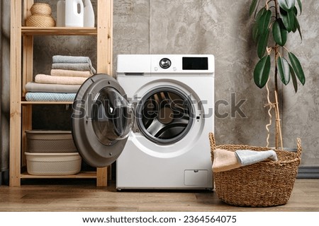 Laundry room interior with washing machine near gray grunge wall Royalty-Free Stock Photo #2364564075