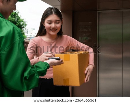 Asian young customer female sign confirm shipping on smartphone from delivery man dispatch order with express service while holding parcel box in front of elevator office company