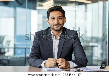 Portrait of a young investor banker at the workplace inside the bank office, a businessman in a business suit looking friendly at the camera, a man at work.