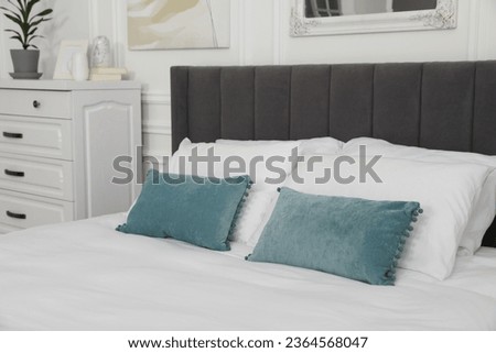 Large comfortable bed with cushions in bedroom. Interior design