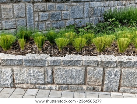 Granite walls made of stone blocks serve as design elements, retaining walls, or seating areas, seats for park visitors. parking for bicycles with metal frames and benches made of horizontal wires Royalty-Free Stock Photo #2364585279