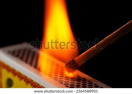 A matchstick lights after it is struck agains the flint surface of a match box. Everything is real, no flame filters Royalty-Free Stock Photo #2364588901