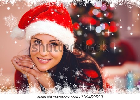 Festive brunette wearing a santa hat against fir tree forest and snowflakes