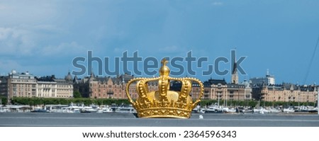 Stockholm, Sweden. Gilded Crown on Skeppsholmsbron Bridge. Royal family symbol at Gamla Stan, Old Town, blue sky background.