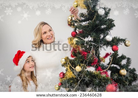 Festive mother and daughter decorating christmas tree against snowflake frame
