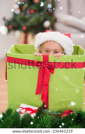 Cute little girl sitting in giant christmas gift against green fir branches with snow